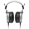 Front view of over-ear headphones with black cushioned ear pads and silver frame showing wired connectors.
