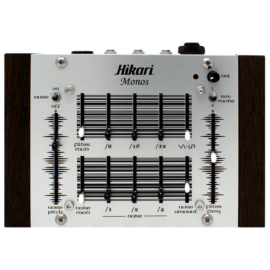 Top-down view of a Hikari Monos synthesizer with sliders, toggle switches, rotary knob, and 3.5mm jacks on a wood-sided metal panel.