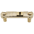 Gold metal wraparound bridge for a guitar with screws and two mounting posts visible.