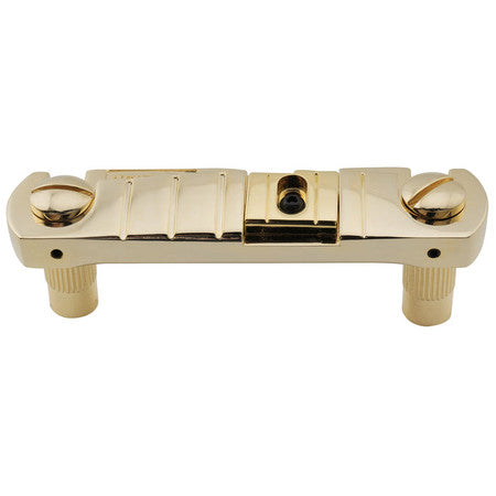 Gold metal wraparound bridge for a guitar with screws and two mounting posts visible.
