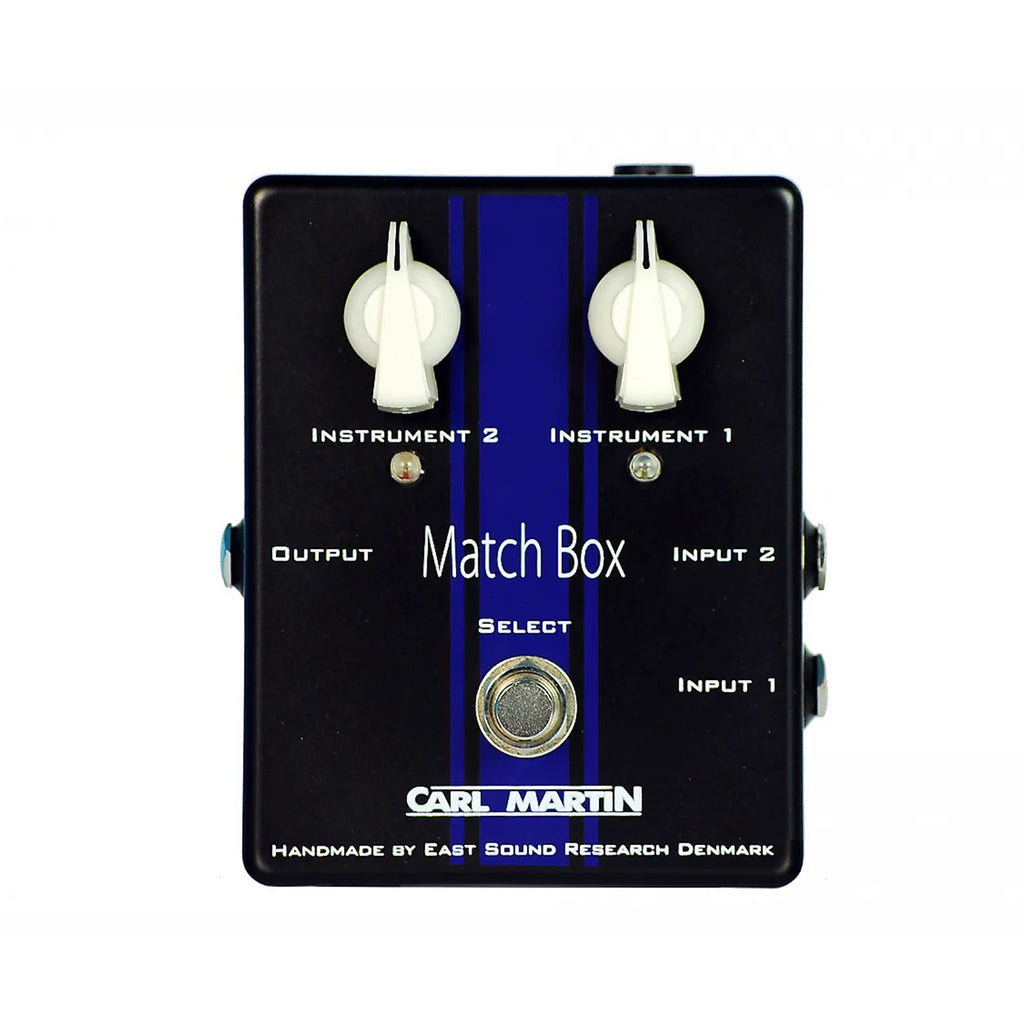 Black rectangular audio switching pedal with two white rotary knobs, one footswitch, and multiple 1/4 inch jacks.
