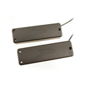Two black rectangular pickups with wires extending from one end, showing embossed logos on their surfaces.