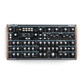 Top-down view of a black synthesizer with many knobs, sliders, buttons, and a digital display showing 'NOVATION PEAK'.