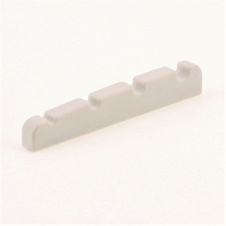 Off-white plastic guitar or bass string nut with four notches for strings.