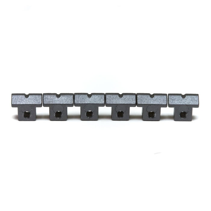 Six black metal saddles for guitar bridge arranged in a straight line on a white background.