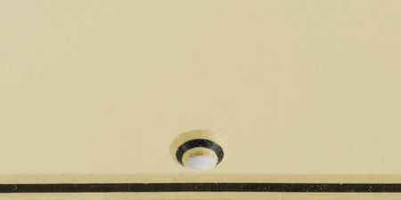 Close-up view of a cream and black layered plastic pickguard blank for guitar.