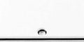Close-up view of a white surface with a small black and white circular detail and a black horizontal line.