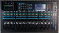 Top view of a digital audio mixer with multiple faders, knobs, push buttons, and two touchscreen displays.