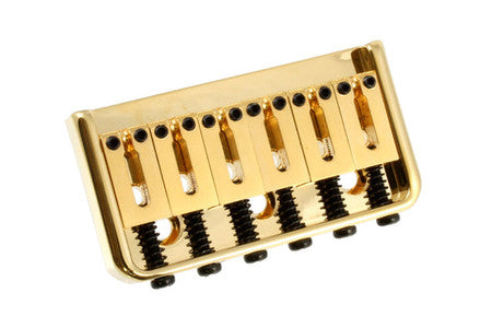 Gold-colored metal bridge with six saddles and six spring-loaded screws for string height adjustment.