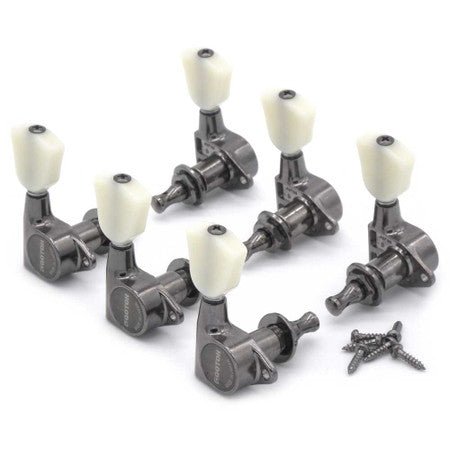 Set of six black metal guitar tuning pegs with white tuning knobs and mounting screws on a white background.