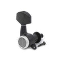 Black individual guitar tuner with silver ring and accompanying screw on white background.