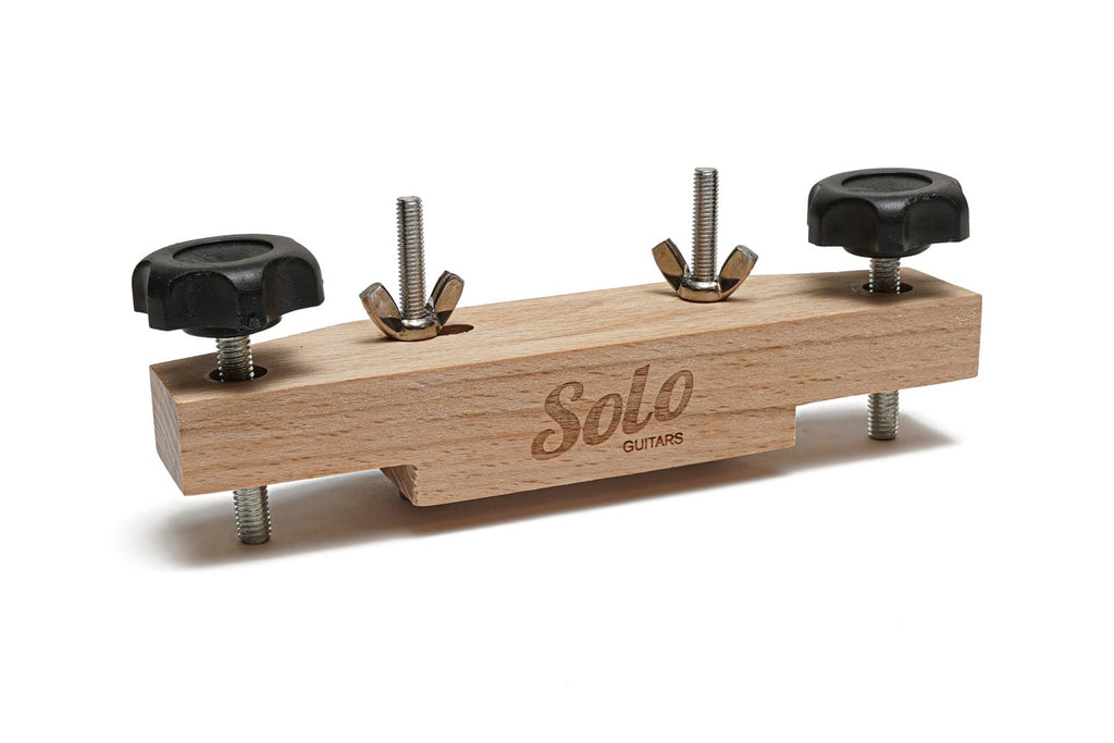Wooden rectangular clamp with metal screws and black knobs, labeled Solo Guitars, shown on white background.