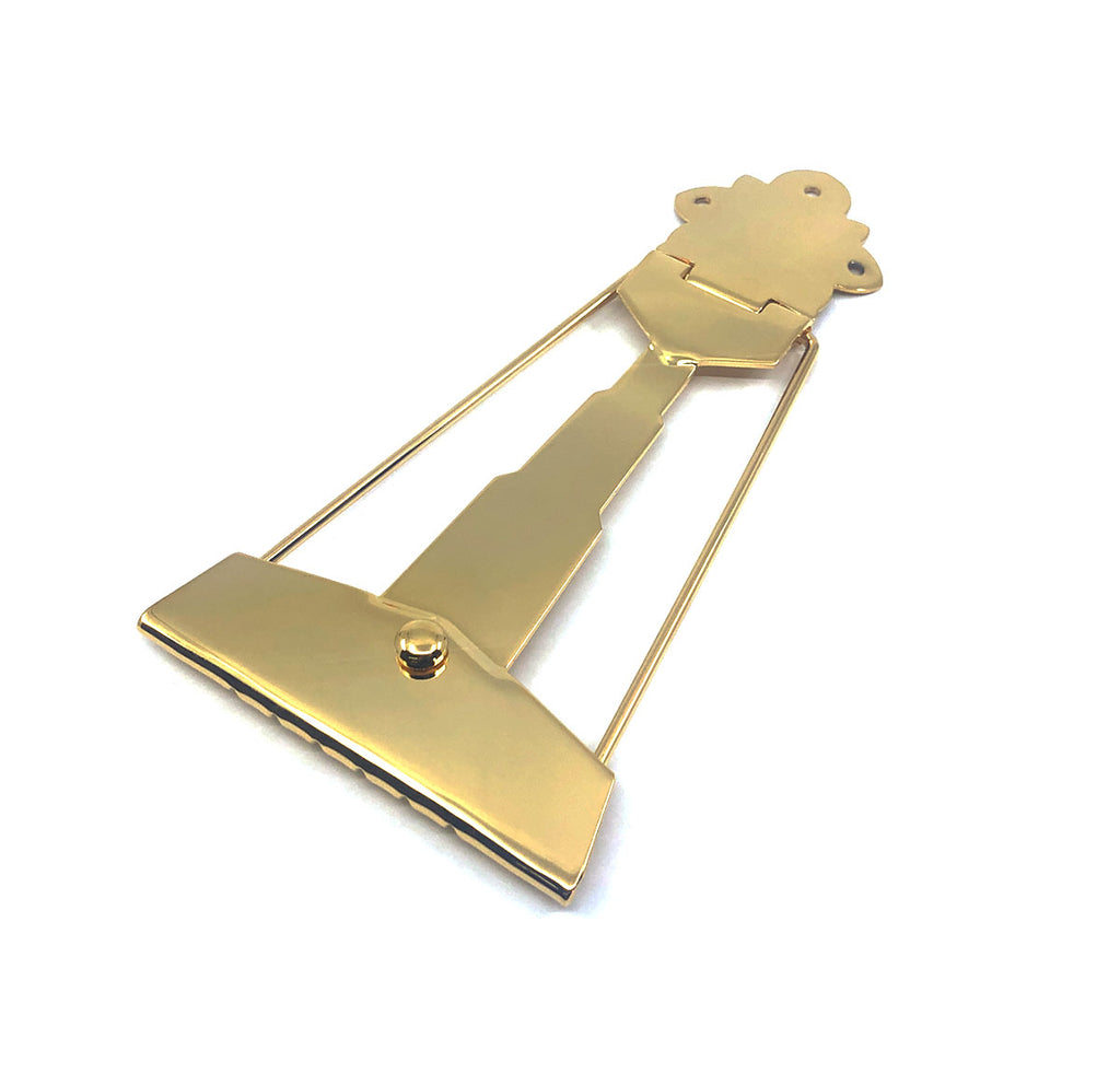 Gold-colored metal guitar tailpiece with decorative top and string slots at the bottom.