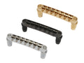 Three guitar bridges in gold, black, and silver colors shown on a white background.