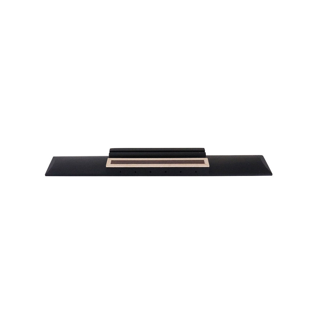 A black classical guitar bridge with a natural wood accent strip and six string holes.