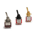 Three toggle switches with metal and plastic parts in silver, black, and gold colors on a white background.