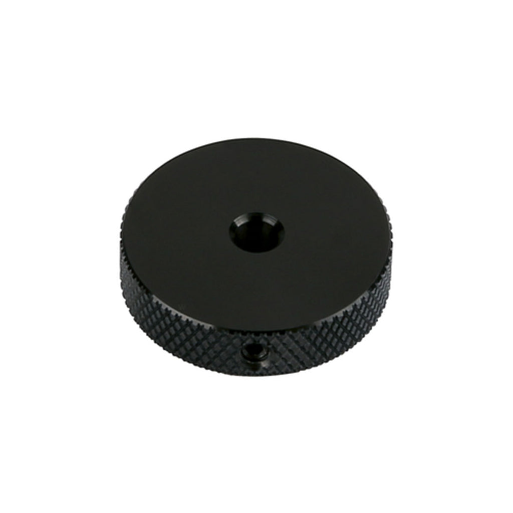 Black circular metal control knob with textured grip and a central hole.