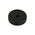 Black circular metal control knob with textured grip and a central hole.