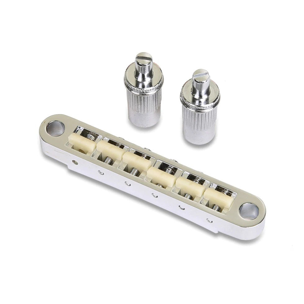 Silver metal guitar bridge with off-white nylon saddles and two matching large posts on a white background.