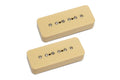 Two cream-colored P90 style guitar pickups with metal pole screws on a white background.