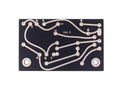 Black printed circuit board with copper traces and labeled solder pads for electronic components.