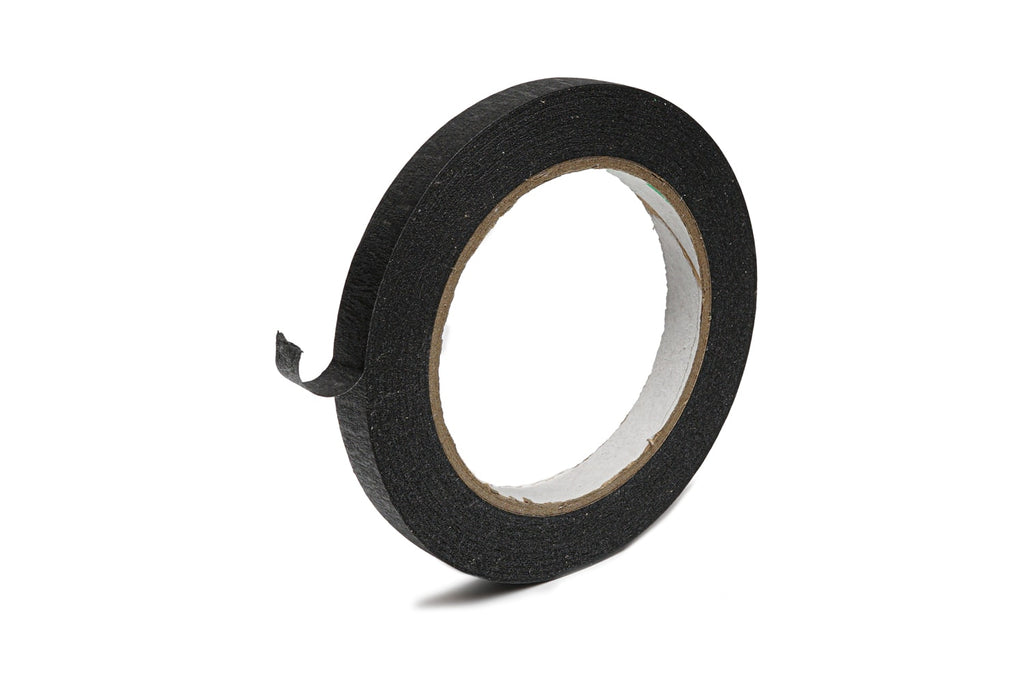 Roll of black paper tape with a small piece unrolled on a white background.