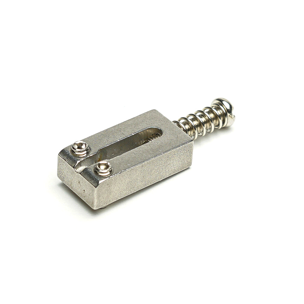 Single metallic rectangular guitar saddle piece with two screws and attached spring on white background.