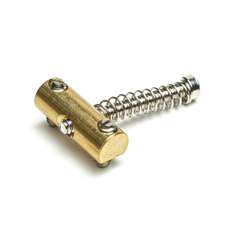 Metal guitar string saddle with attached tension spring and three screws on white background.