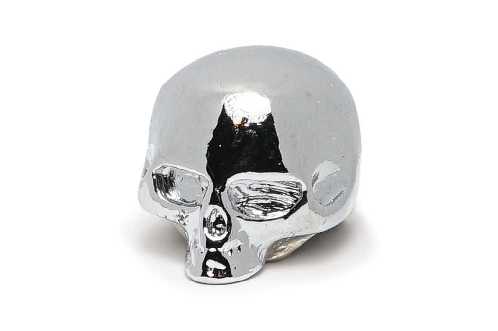 Shiny chrome skull-shaped metal knob with hollow eye sockets and nose, viewed from a slightly angled front side.