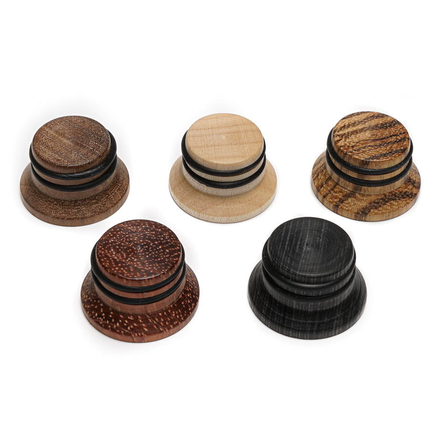 Five wooden control knobs in different wood colors with black rubber rings, arranged on a white background.