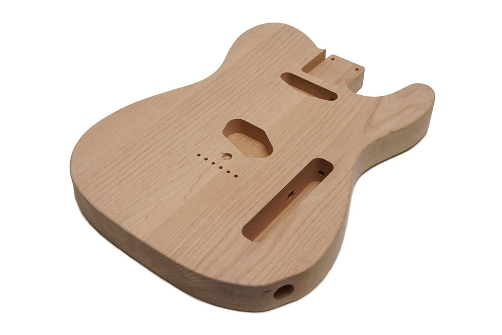 Unfinished natural wood guitar body with routed cavities and holes for components.