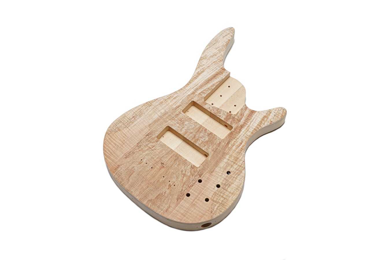 Unfinished wood bass guitar body with two pickup cavities and multiple drilled holes for hardware.