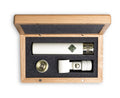 White cylindrical microphone with gold connector and accessories in a wooden box with foam insert.