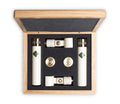Two white cylindrical microphones and accessories in a wooden box with black foam insert.
