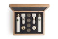 Open wooden case containing two white microphones, two clips, and four round metal capsules on black foam