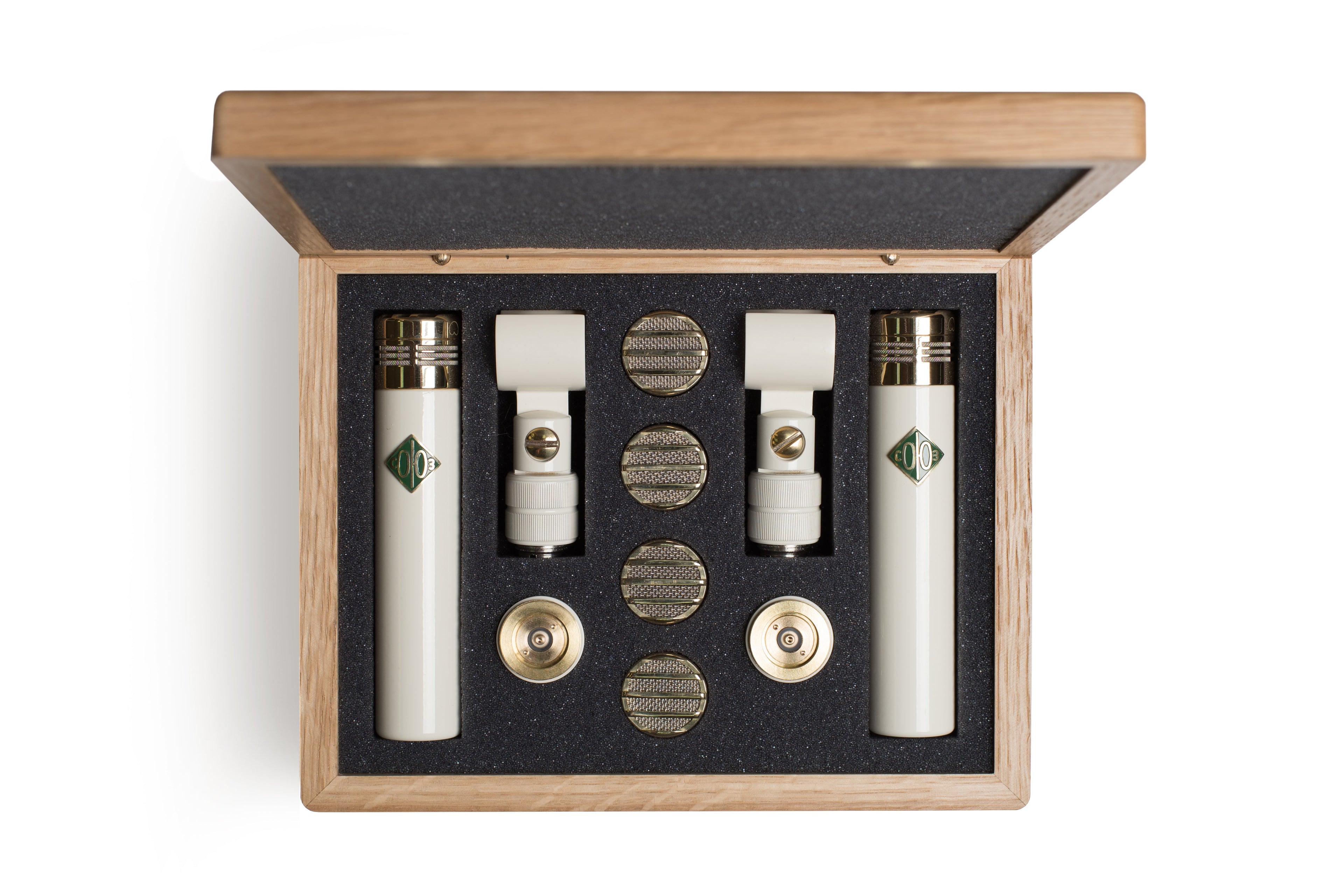 Open wooden case containing two white microphones, two clips, and four round metal capsules on black foam