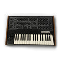 Black and wooden vintage synthesizer keyboard with multiple knobs and switches labeled Pro-One.