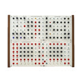 Modular synthesizer eurorack unit with knobs, jacks, and buttons on white panel with wooden sides.