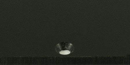 Close-up of a black matte surface with a single recessed hole.
