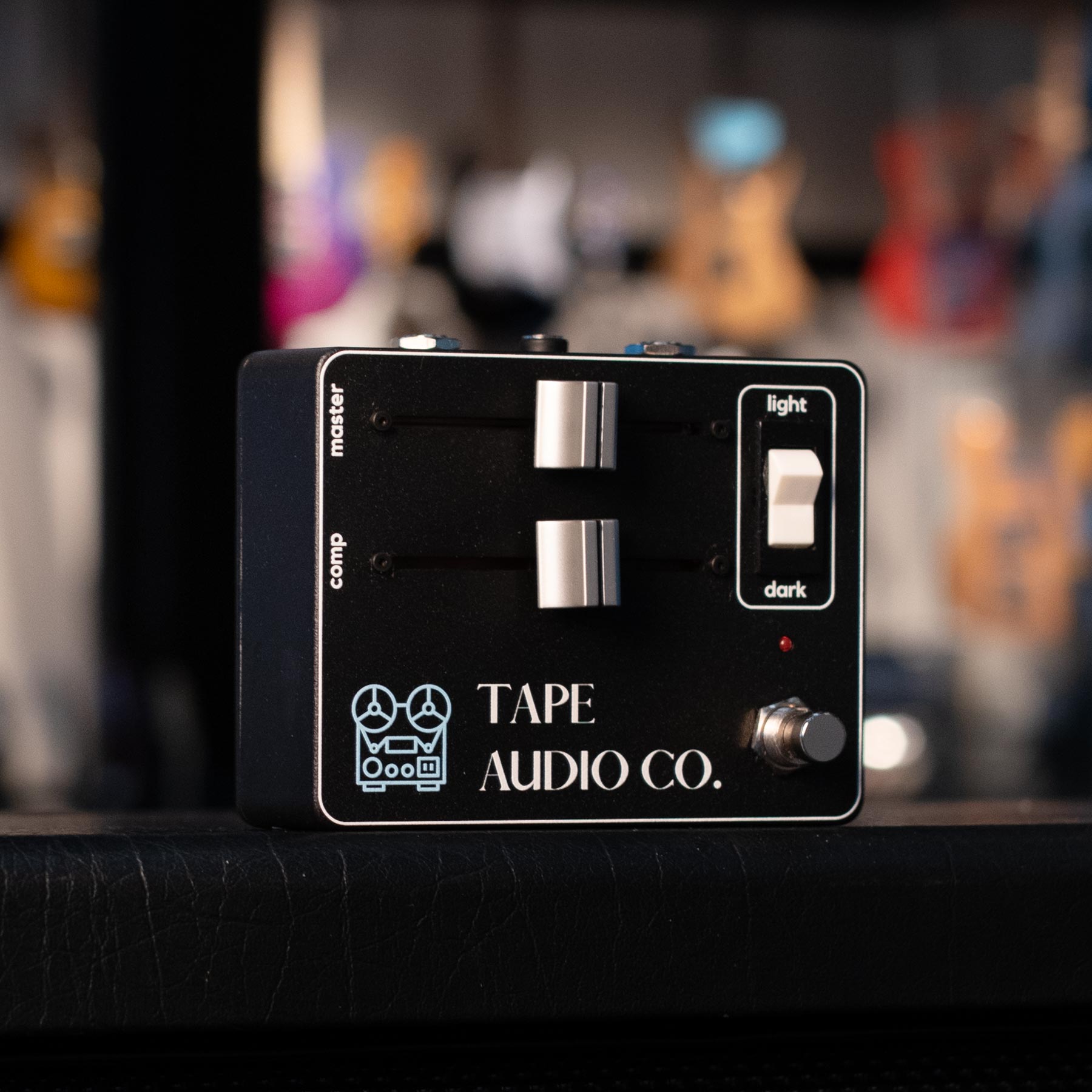 Black guitar pedal with two sliders, a toggle switch, a footswitch, and Tape Audio Co. branding.