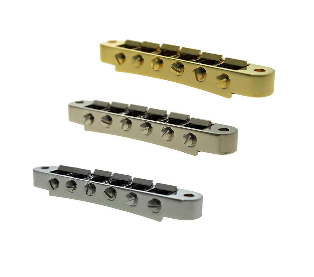 Three metal guitar bridge pieces in gold, nickel, and chrome finish shown from an angled top view.
