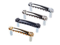 Four metal guitar tailpieces in silver, black, nickel, and gold finishes displayed on a white background.