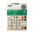 Top-down view of a cream-colored electronic music layering machine with green and orange buttons and a speaker on the top right.