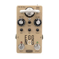 Beige guitar effects pedal with knobs, footswitches, a tube, and labeled controls for boost, bypass, bass, mid, and treble.