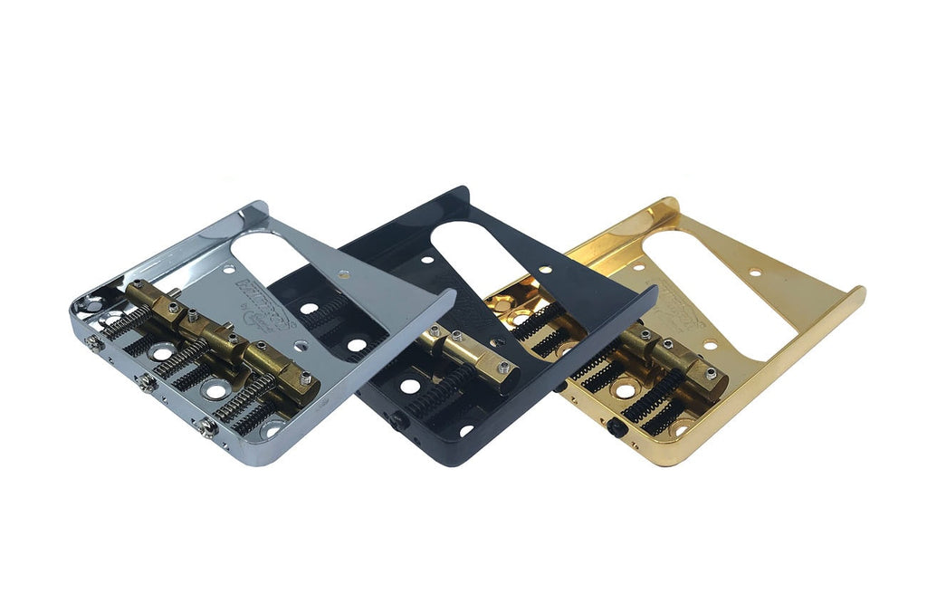 Three metal ashtray-style guitar bridges with brass saddles in silver, black, and gold finishes.
