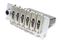 Silver metal guitar bridge unit with six saddles and mounting posts viewed at an angle.