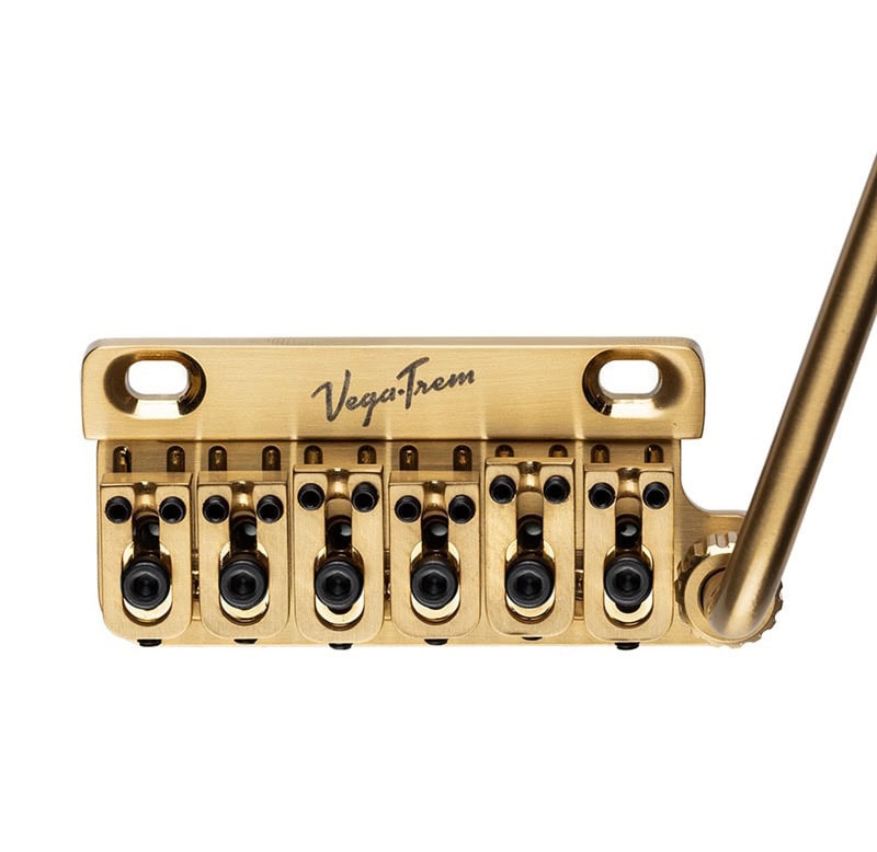 Gold-colored guitar tremolo bridge system with six string saddles and a tremolo arm attached.