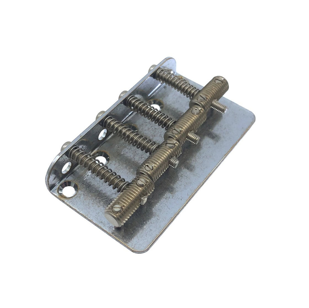 A metal bass bridge component with four saddles and adjustment screws on a rectangular base plate.
