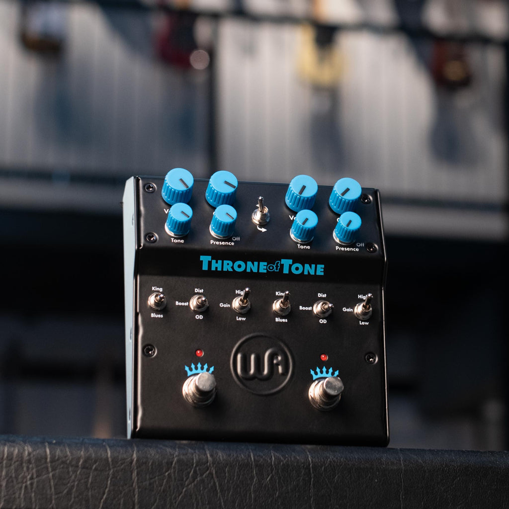 Black dual-sided overdrive pedal with blue knobs, toggle switches, and two footswitches on a textured surface.