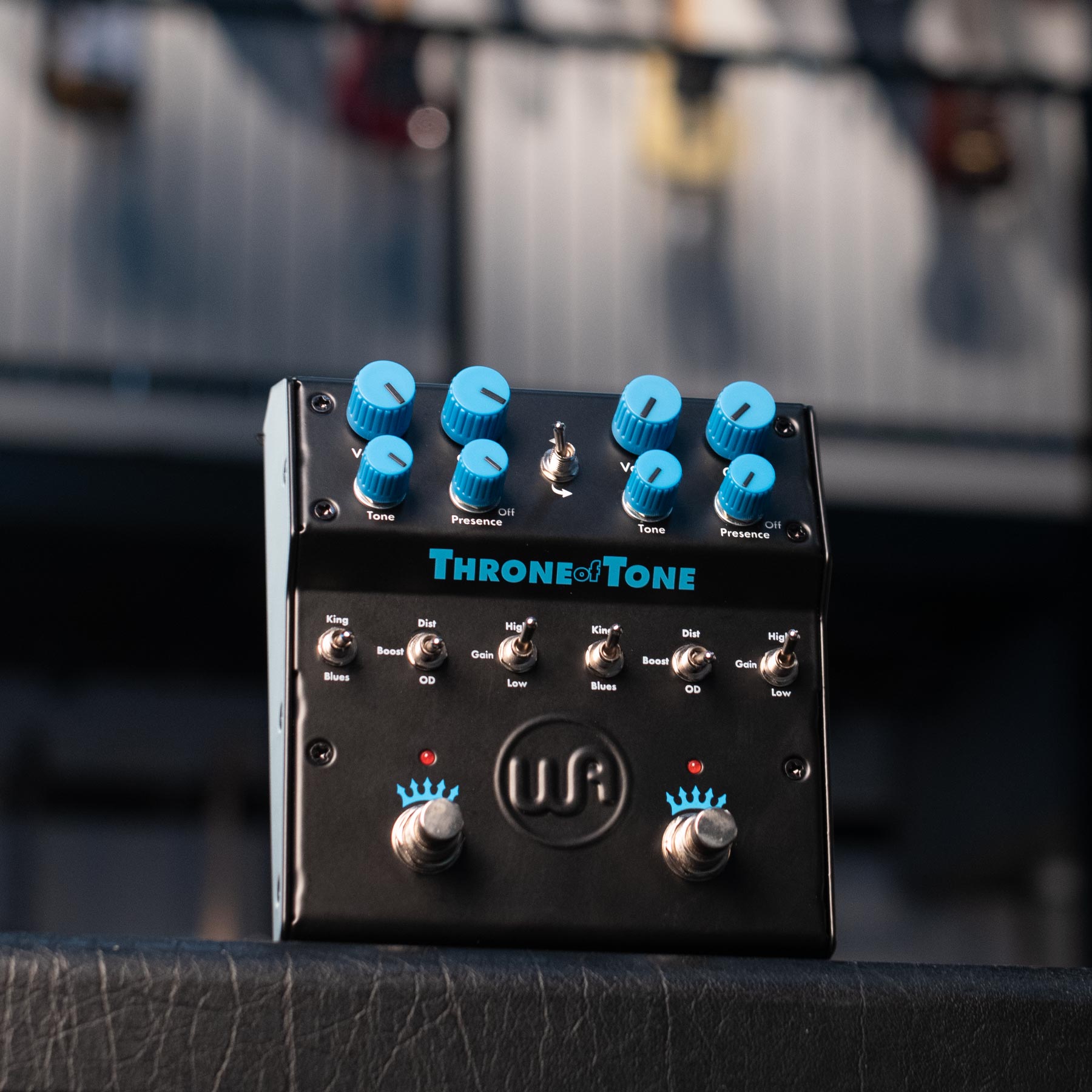 Black dual-sided overdrive pedal with blue knobs, toggle switches, and two footswitches on a textured surface.